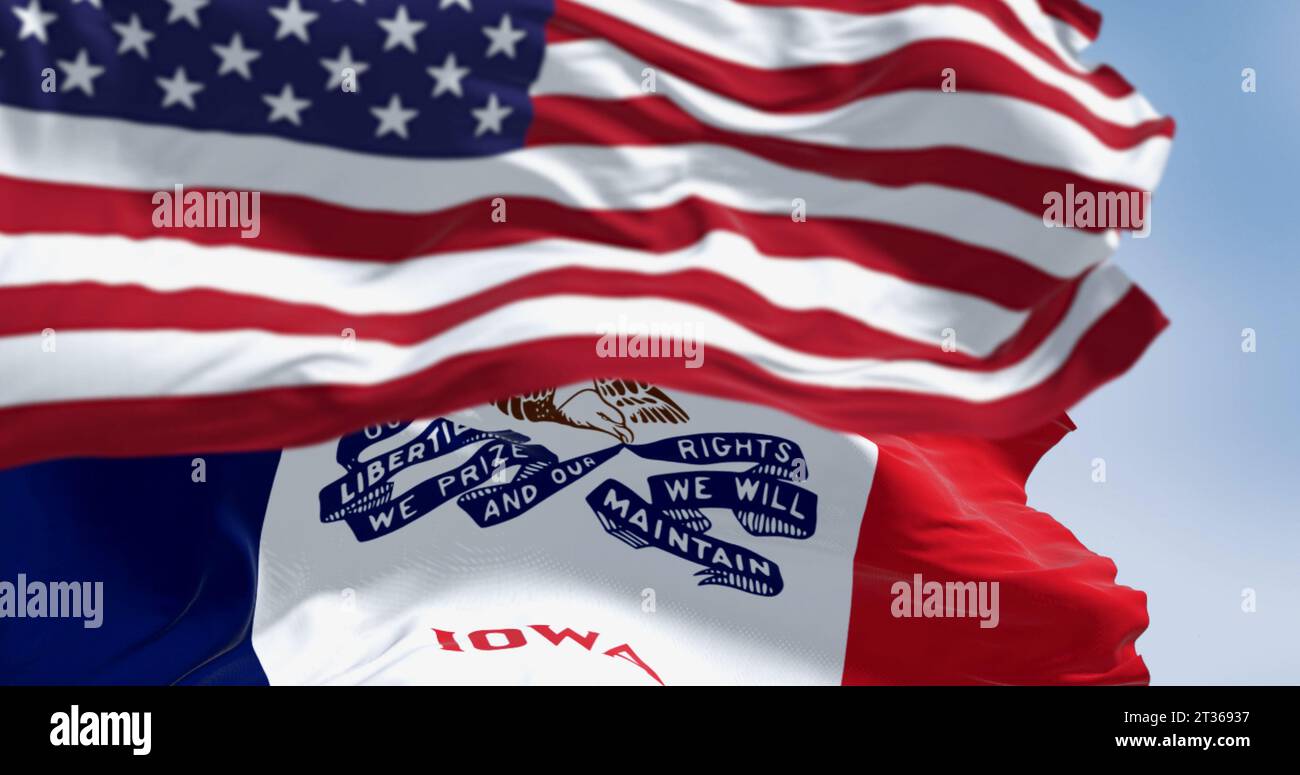 Nahaufnahme der Iowa-Staatsflagge, die an einem klaren Tag im Wind mit der amerikanischen Nationalflagge winkt. 3D-Darstellung. Geriffeltes Material. Selektiver Fokus Stockfoto