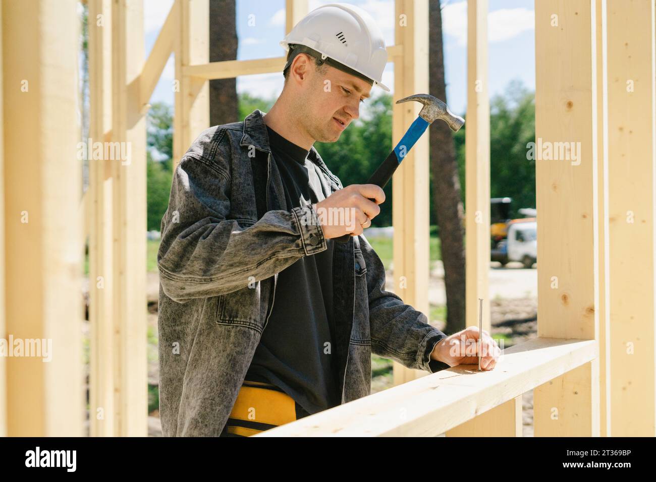 Ingenieur schlägt auf der Baustelle mit Hammer auf den Nagel Stockfoto