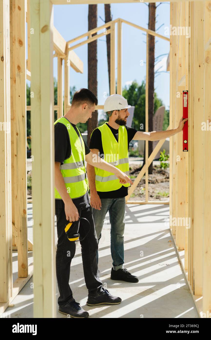 Ingenieure messen mit Nivellierwerkzeug und diskutieren vor Ort Stockfoto