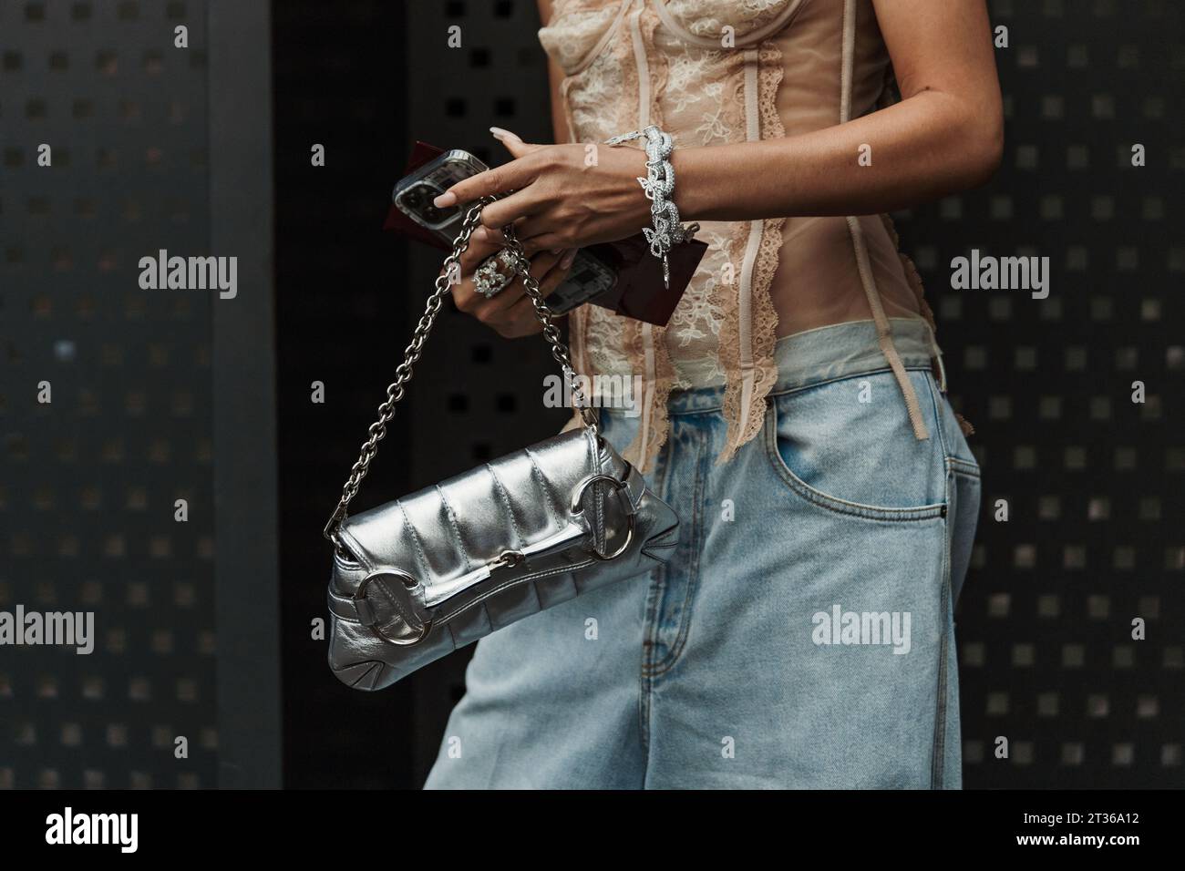 Aleali May trägt ein schulterfreies Oberteil, eine hellblaue, breite Jeans und eine silberne Gucci-Tasche vor der Gucci-Show während der Mailand Fashion Week im Frühjahr/Sommer 2024. Stockfoto