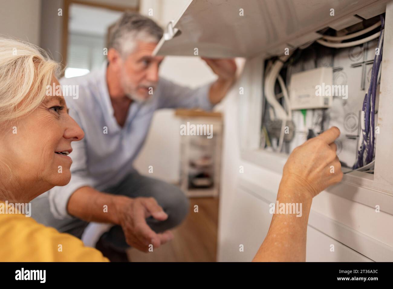 Frau, die das elektrische Kabel im Sicherungskasten mit einem Mann zu Hause untersucht Stockfoto