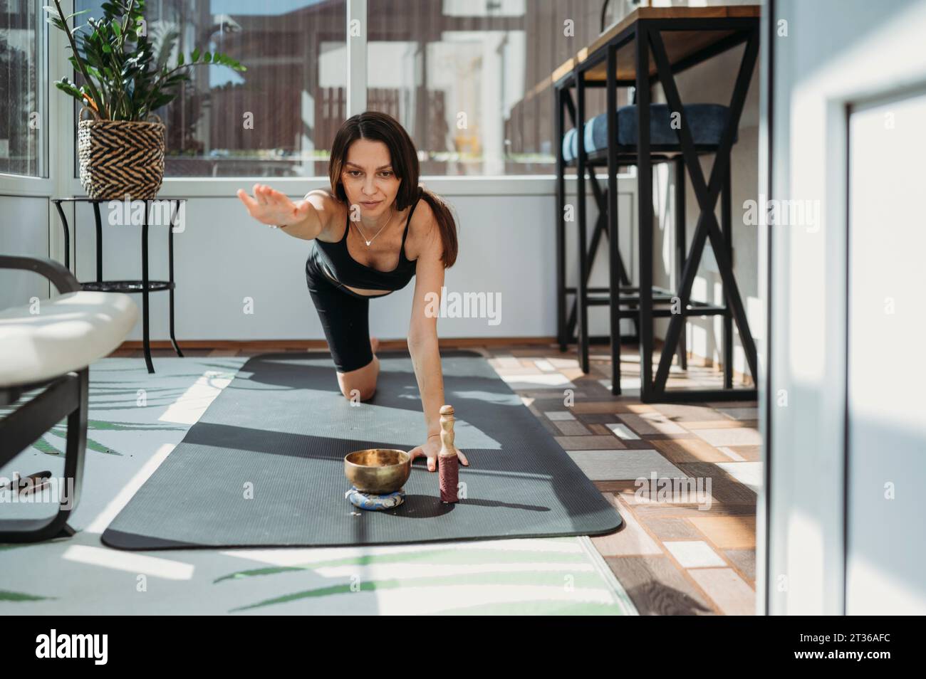 Entschlossene Frau, die zu Hause eine Balancing Table Pose auf Yogamatte übt Stockfoto