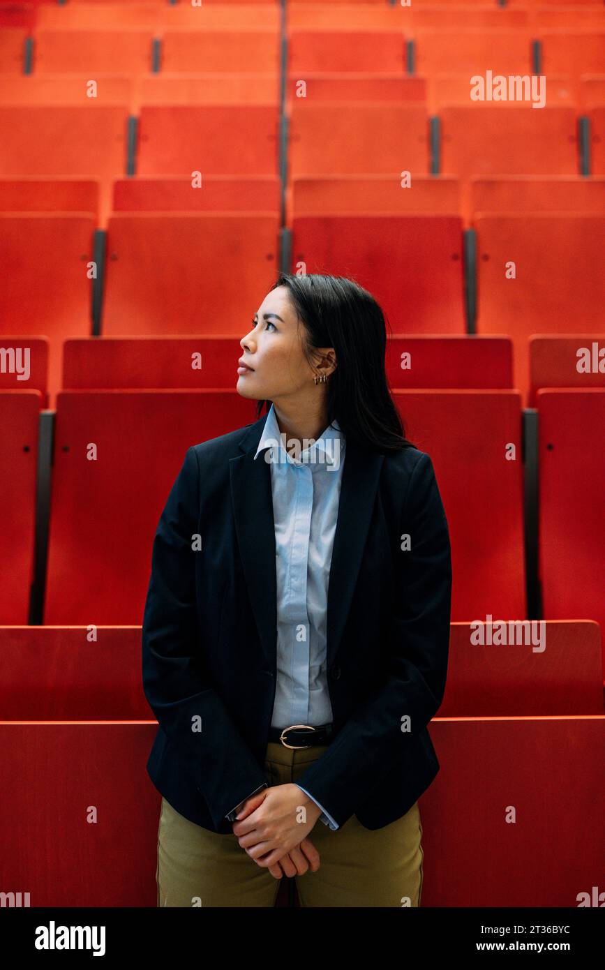 Geschäftsfrau steht vor roten Sitzen im Auditorium Stockfoto