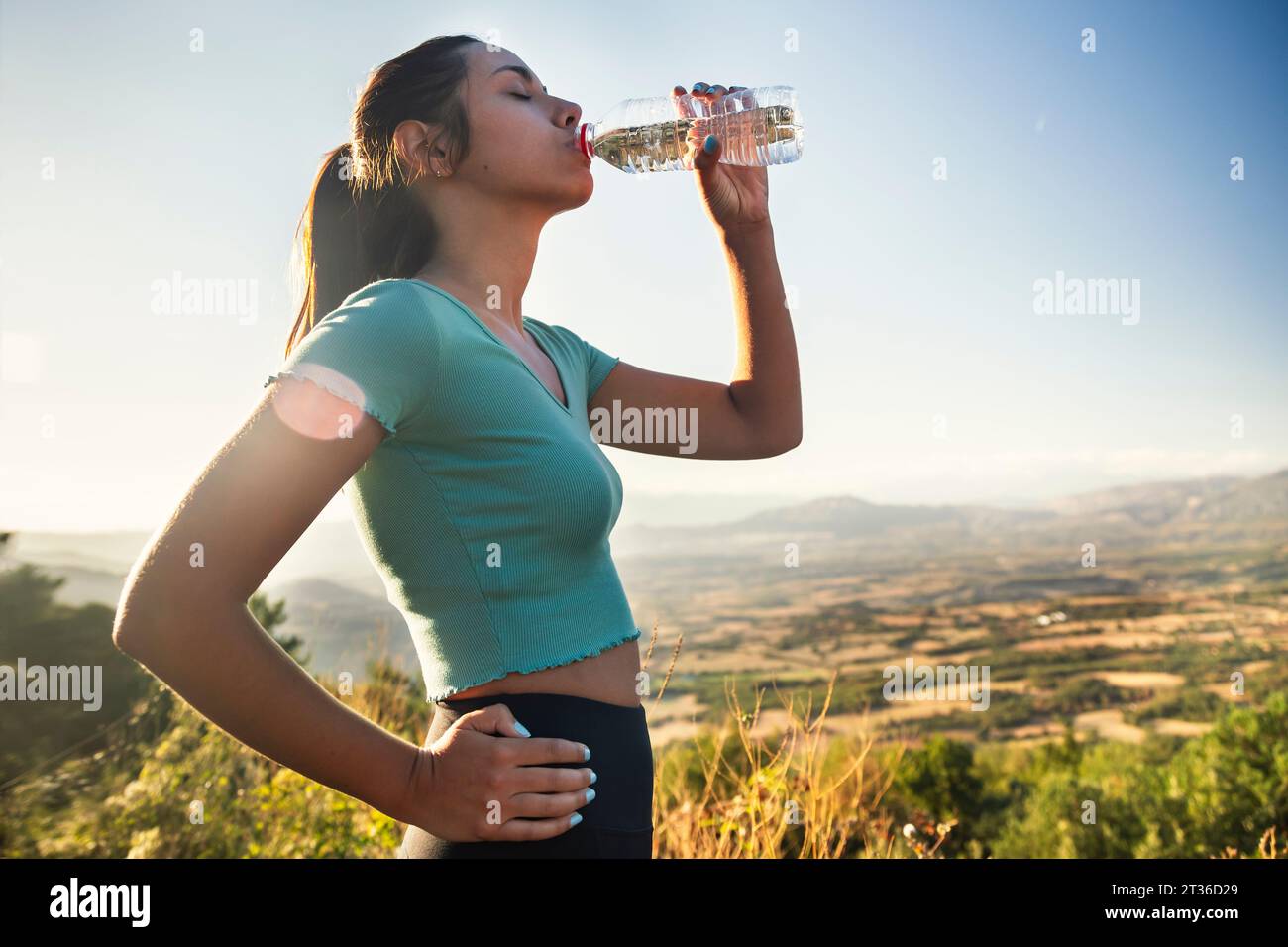 Durstige Frau trinkt Wasserflasche an sonnigem Tag Stockfoto