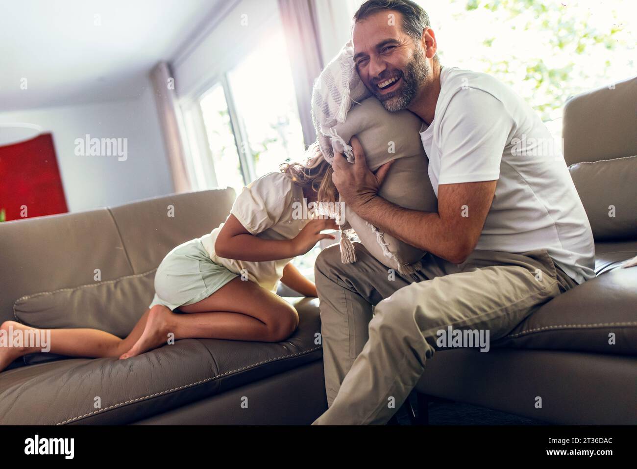 Der glückliche Vater spielt gern mit der Tochter auf dem Sofa Stockfoto