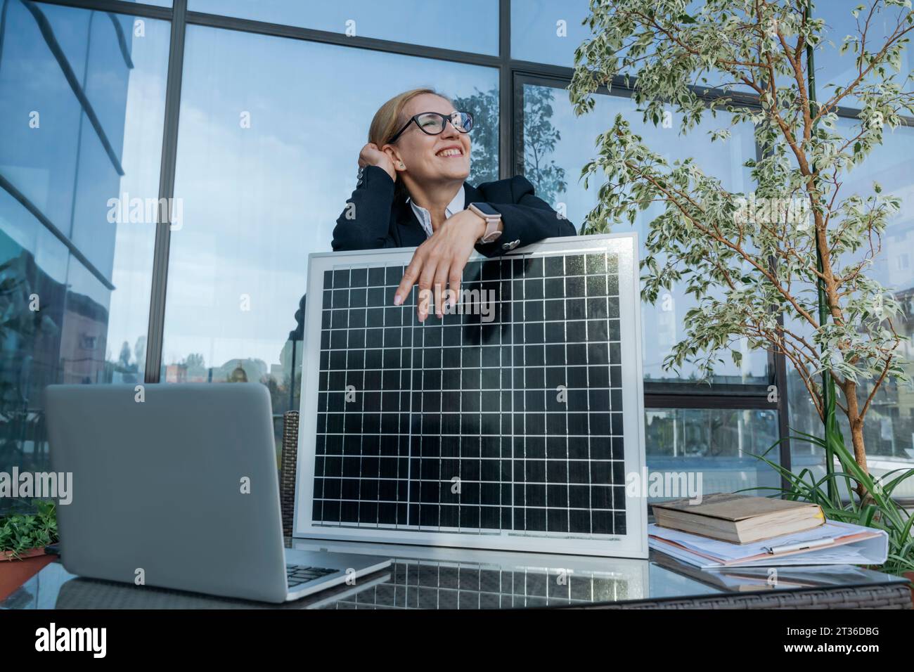 Durchdachte Geschäftsfrau mit Sonnenkollektor auf der Terrasse des Business Centers Stockfoto
