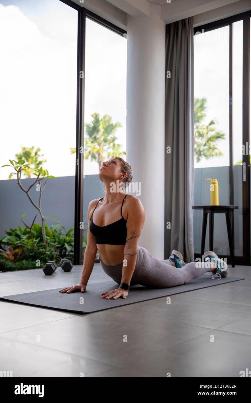 Aktive Frau, die zu Hause Yoga auf der Matte macht Stockfoto