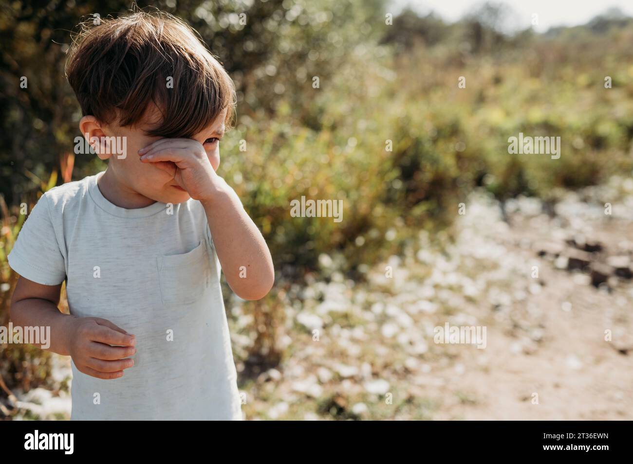 Trauriger Junge, der am sonnigen Tag im Feld weint Stockfoto