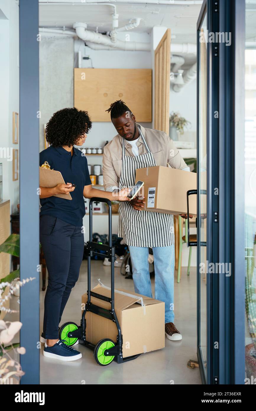Frau, die den QR-Code aus dem Paket im Café fotografiert Stockfoto