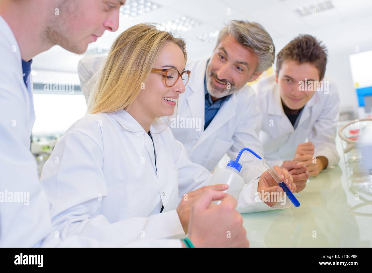 Die Schüler scherzen mit dem Lehrer, während sie Experimente durchführen Stockfoto