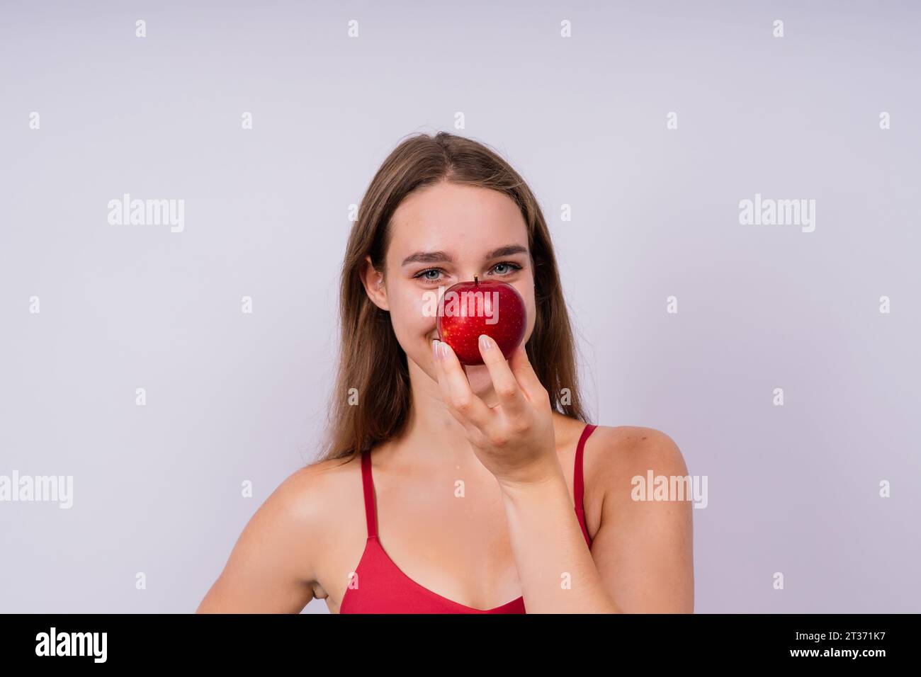 Frühstück am Morgen. Frau mit gesunden Zähnen, die Äpfel auf einem grauen isolierten Hintergrund hält. Stockfoto