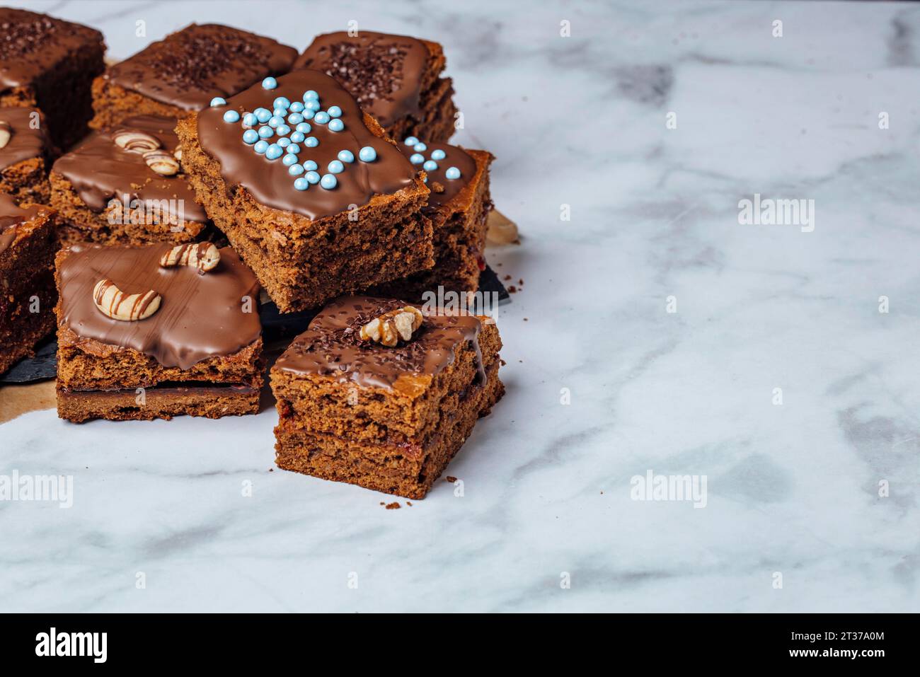 Mit Marmelade gefüllte Brownies mit Schokoladenglasur, dekoriert mit Nüssen, Schokoladenstreuseln und Zuckerperlen, Kopierraum Stockfoto