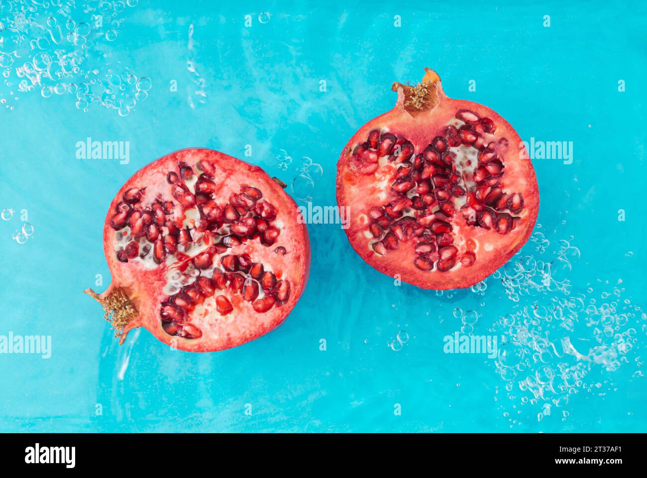 Trendige Szene mit frischem Granatapfel im Wasser. Minimales Naturhintergrundkonzept. Kreatives Layout für gesunde Früchte. Granatapfelästhetik. Flache Lagen. Stockfoto