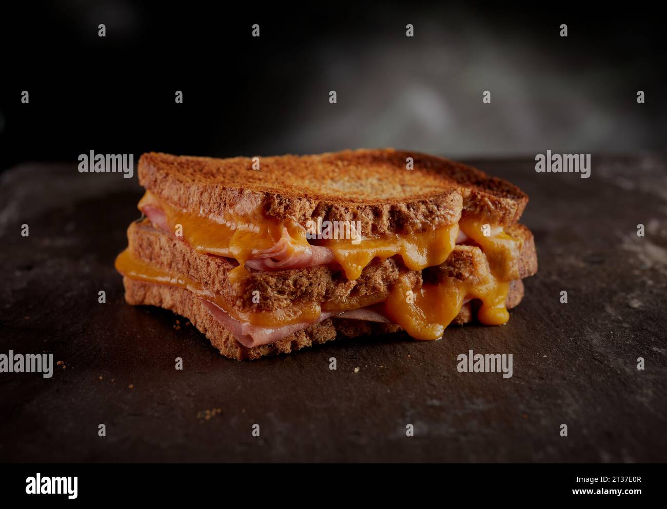 Mit Käse und Schinken getoastetes Sandwich, der Käse tropft an den ...