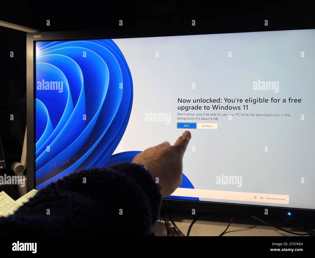 Paris, Frankreich - 18. Februar 2023: Eine männliche Hand zeigt auf eine auffällige Nachricht auf einem großen Touchscreen mit der Aufschrift „jetzt freigeschaltet“ – Sie sind berechtigt, ein Upgrade auf Windows 11 durchzuführen Stockfoto