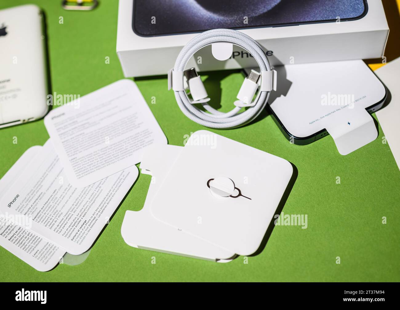 London, UK - 28. September 2023: Während des Auspackens des Apple Computers iPhone 15 Pro Max werden ein sim-Kartenauswurfwerkzeug und ein USB-C-Geflechtkabel neben der Gerätebox auf einem kreativ gestalteten Tisch platziert Stockfoto