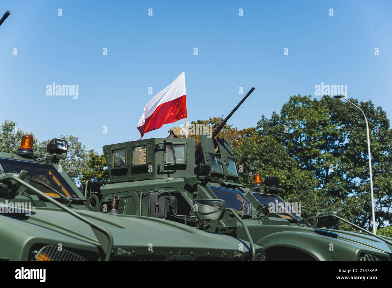 Freiluftparade in Warschau. Weiße und rote polnische Flagge auf einem modernen Militärpanzer gegen blauen Himmel und Bäume. Hochwertige Fotos Stockfoto