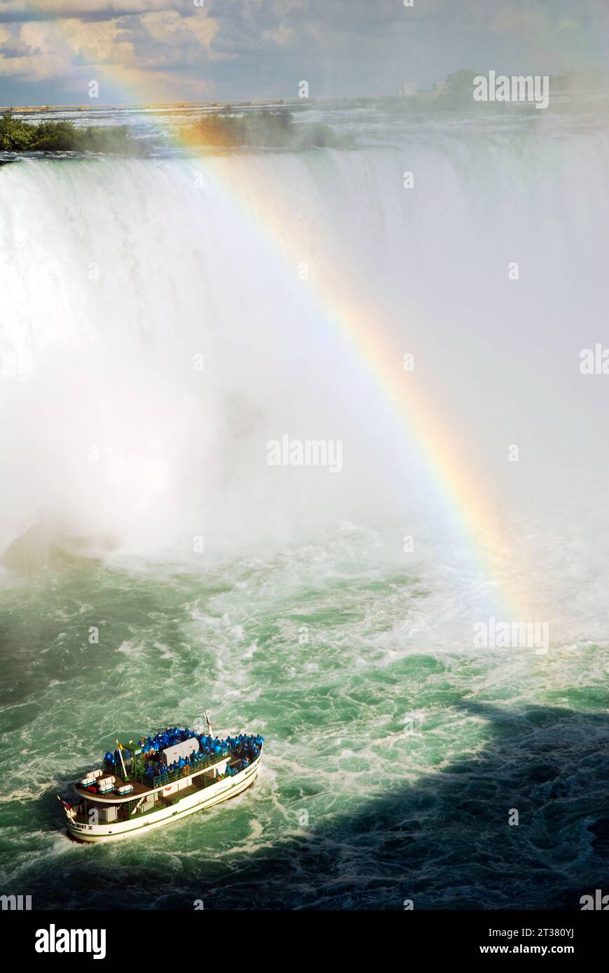 Ein Regenbogen entwickelt sich im Nebel der Niagarafälle, während das Tourboot Maid of the Mist Touristen näher an die Kaskade bringt Stockfoto