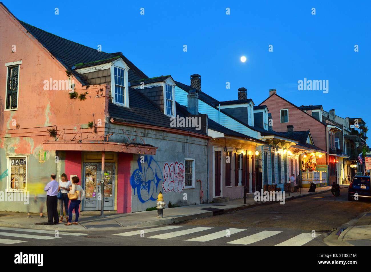 Graffiti marschieren die Mauern historischer Häuser im French Quarter von New Orleans, während der Vollmond über der Stadt aufgeht Stockfoto