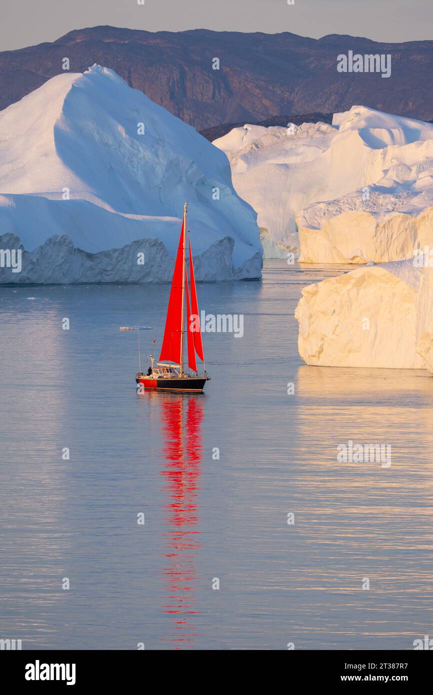 Rote Segel auf der Yacht zwischen großen Eisbergen Stockfoto