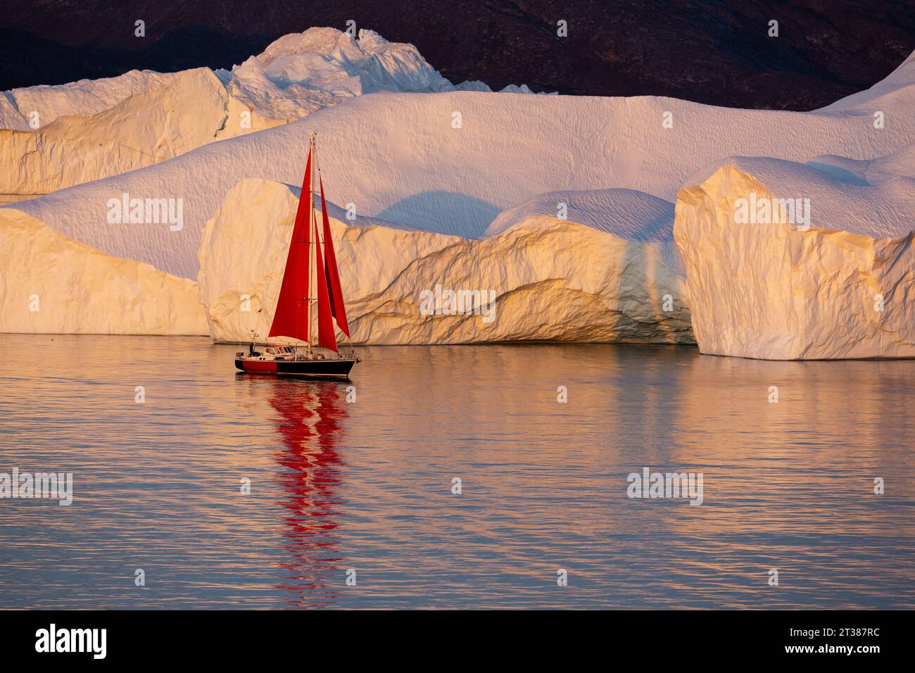 Rote Segel auf der Yacht zwischen großen Eisbergen Stockfoto