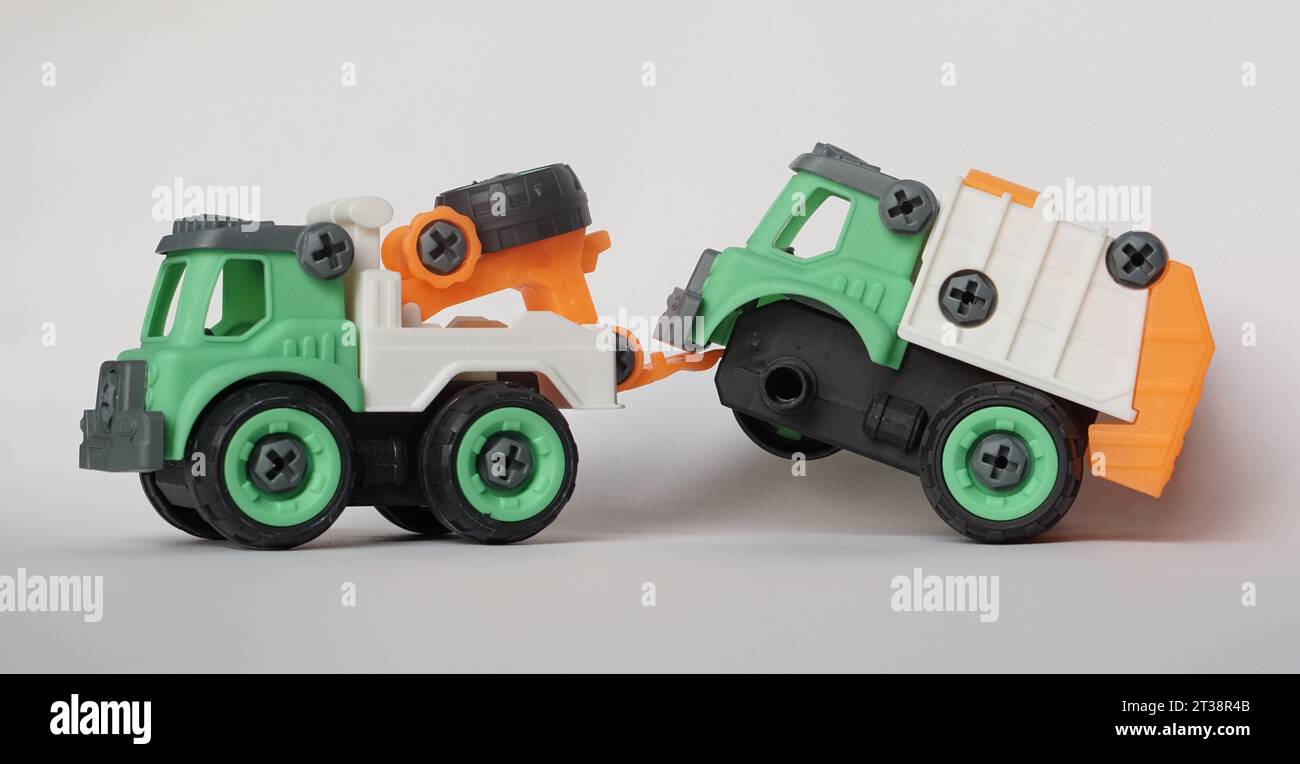 DIY-Kunststoff-Truck-Spielzeug isoliert auf weiß. Schwerlastfahrzeug schleppt beschädigten Müllwagen ab. Das selbstgebaute Spielzeug steigert die Kreativität der Kinder. Stockfoto