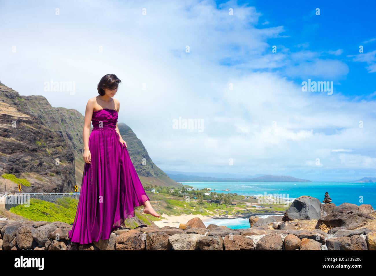 Junge Frau in formellem lila Kleid am Makapu'u Aussichtspunkt mit Blick auf den Makapu'u Strand und den hawaiianischen Ozean auf Oahu, Hawaii Stockfoto