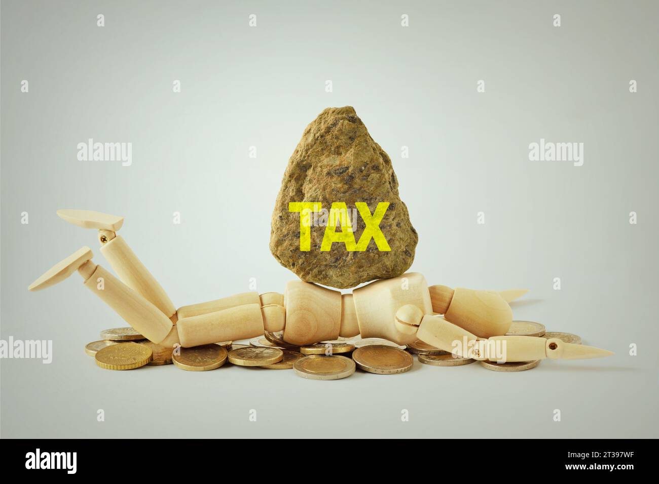 Hölzerne Schaufensterpuppe unter schwerem Felsbrocken mit dem Wort Steuer - Konzept der Zerquetschung durch das Gewicht der Steuern Stockfoto