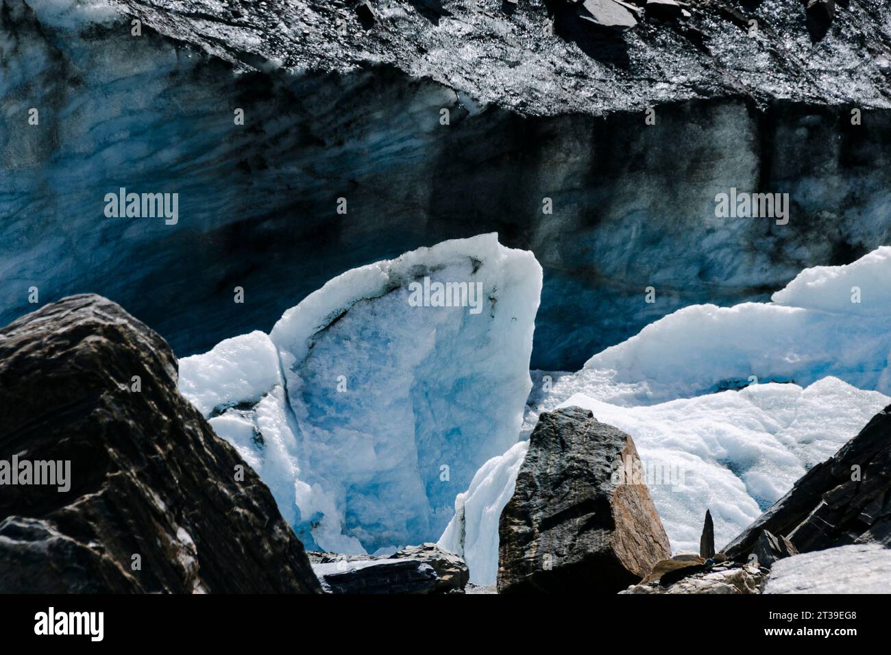 Nahaufnahme eines Gletschers mit eisigen Formationen inmitten von Felsen unter Sonnenlicht. Stockfoto