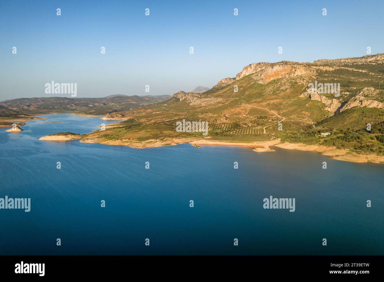 Aus der Vogelperspektive des Flusswassers, das vom Guadalhorce-Damm von Gobantes in Spanien fließt, vor felsigem, bergigem Gelände unter blauem Himmel Stockfoto