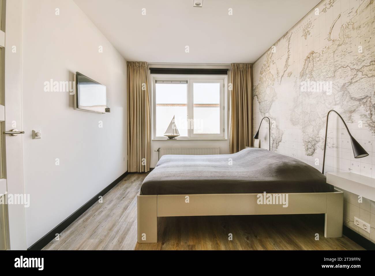 Schlafzimmer mit Bett und Tapete an der Wand vor dem Fernseher in einem modernen Apartment mit hellen Fenstern Stockfoto