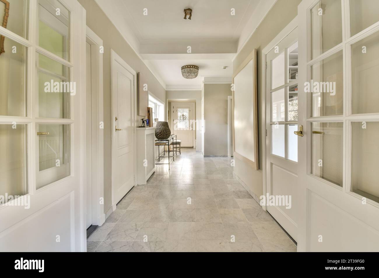 Leerer Flur mit weißen geschlossenen Türen verschiedener Zimmer und Marmorboden in einem modernen, geräumigen Apartment Stockfoto