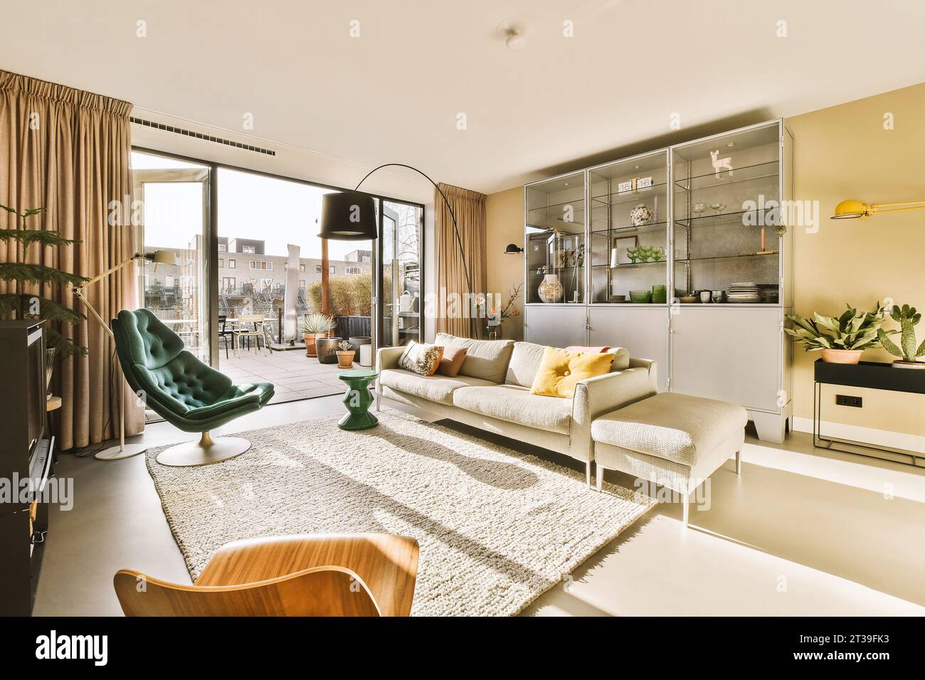 Komfortables Sofa mit Stühlen und Ablage vor dem Fernseher im Wohnzimmer mit großem hellen Fenster im luxuriösen Apartment Stockfoto