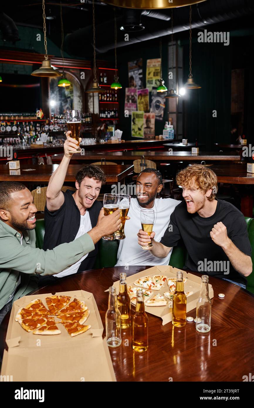 Abends draußen, aufgeregte Männer, die Bier in der Nähe von Pizza in der Bar trinken, männliche Freundschaft Stockfoto