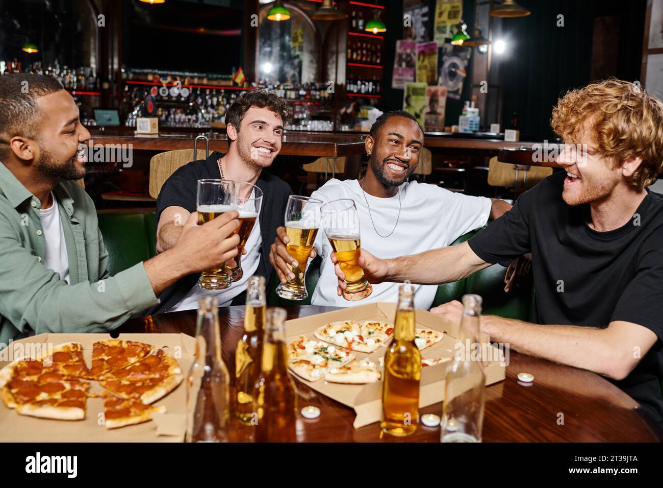 Abends draußen, fröhliche Männer, die Bier in der Nähe von Pizza in der Bar trinken, männliche Freundschaft Stockfoto