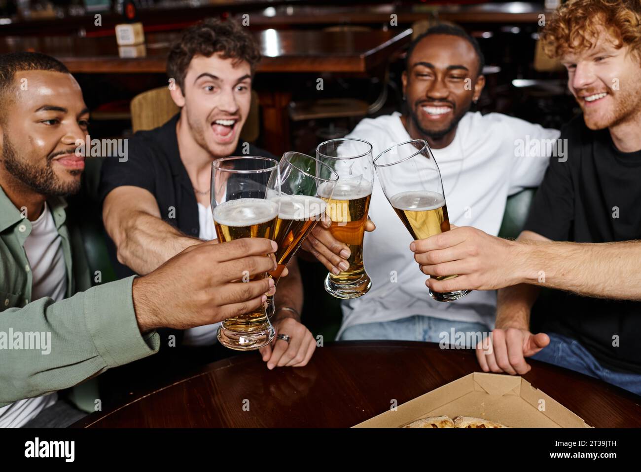 Vier aufgeregte multikulturelle Freunde, die mit einem Glas Bier in der Bar klirren, Männer auf Junggesellenabschied Stockfoto