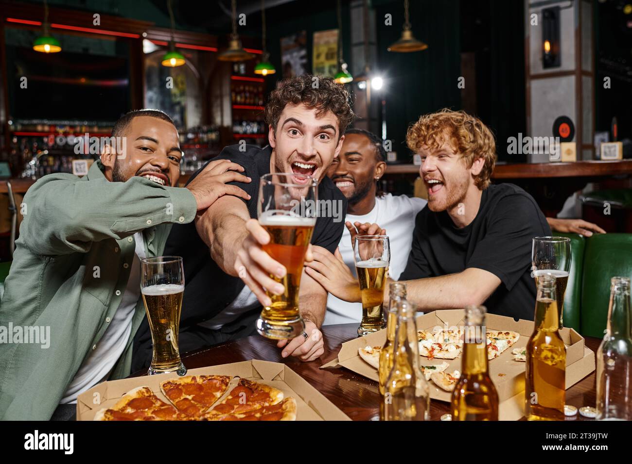 Eine Gruppe aufgeregter multikultureller Freunde, die mit einem Glas Bier in der Bar tosten, Männer auf Junggesellenabschied Stockfoto