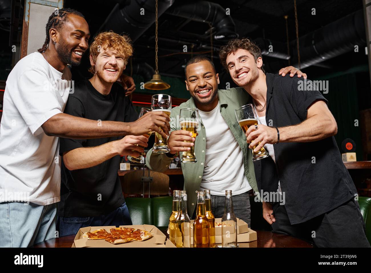 Fröhliche Männer, die mit Gläsern Bier in der Bar während der Junggesellenabschied tosten, männliche Freundschaft Stockfoto