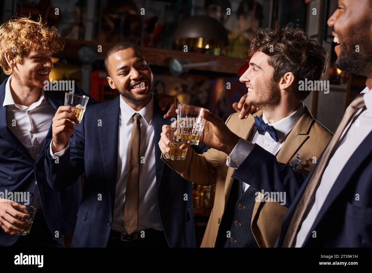 Junggesellenabschied, fröhliche Männer, die mit Gläsern Whiskey in der Bar tosten, Bräutigam und beste Männer Stockfoto