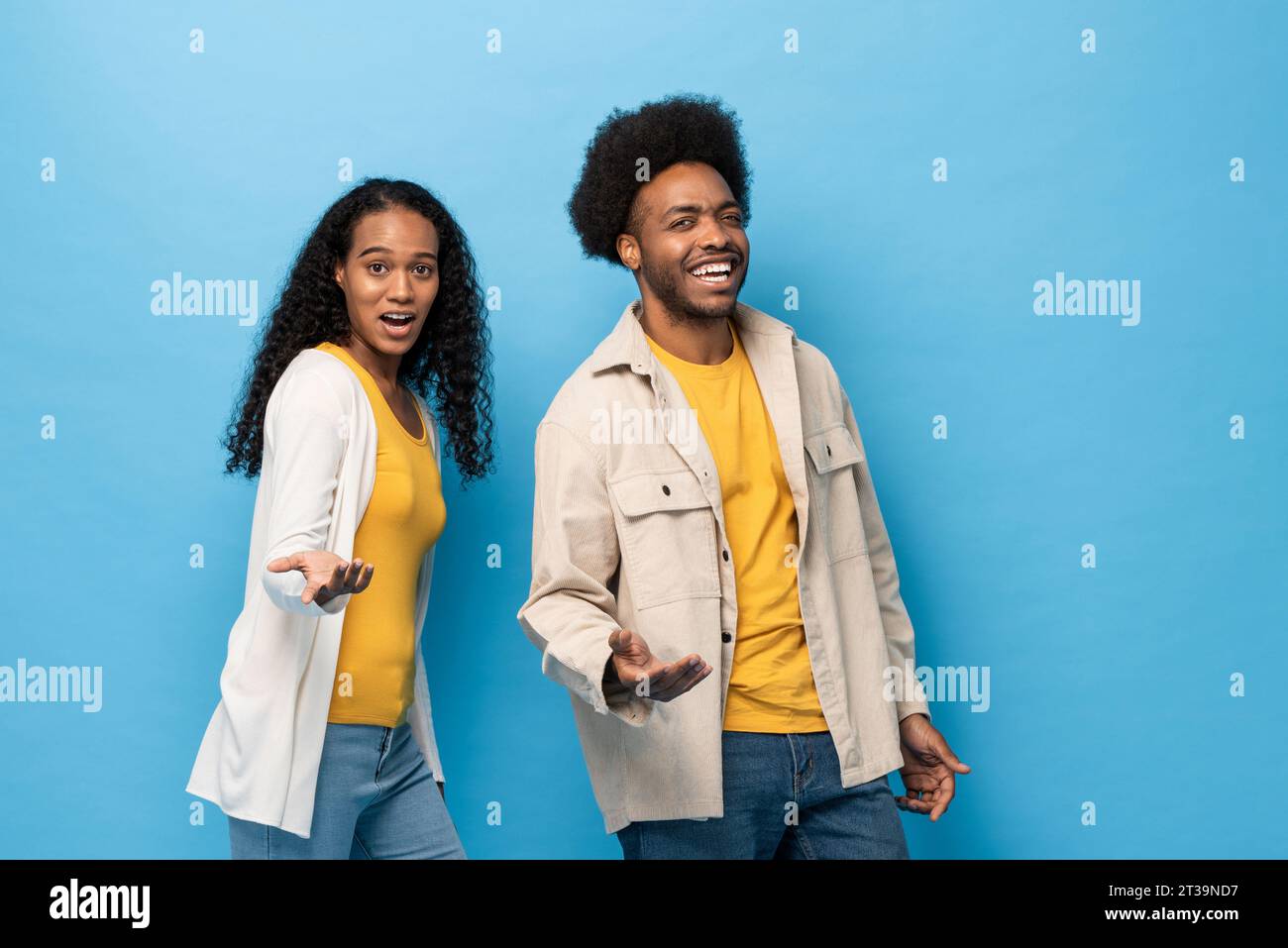 Glückliches lächelndes afroamerikanisches Paar, das mit geöffneter Hand in hellblauem Studio-isoliertem Hintergrund steht Stockfoto