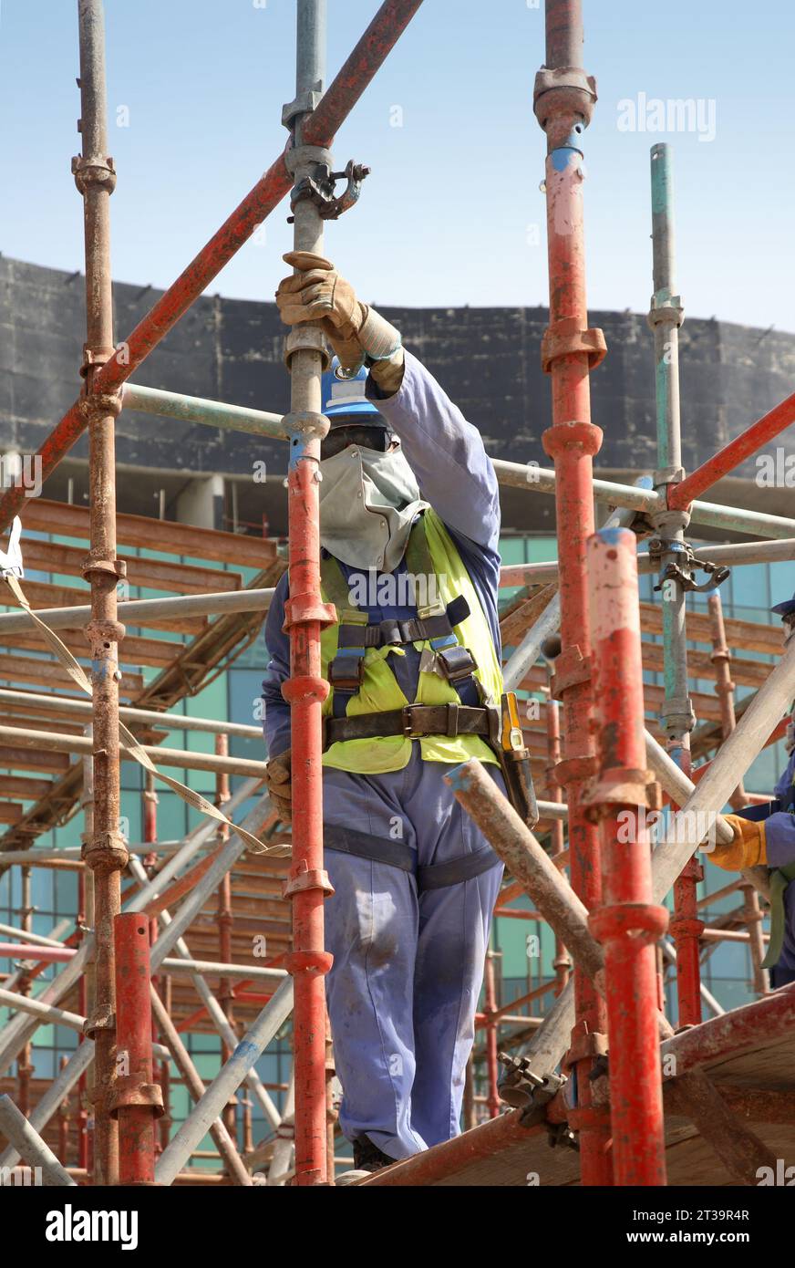 Ausländische Arbeiter aus Indien und Pakistan bauen Gerüste auf einer großen Baustelle in Abu Dhabi, VAE. Stockfoto