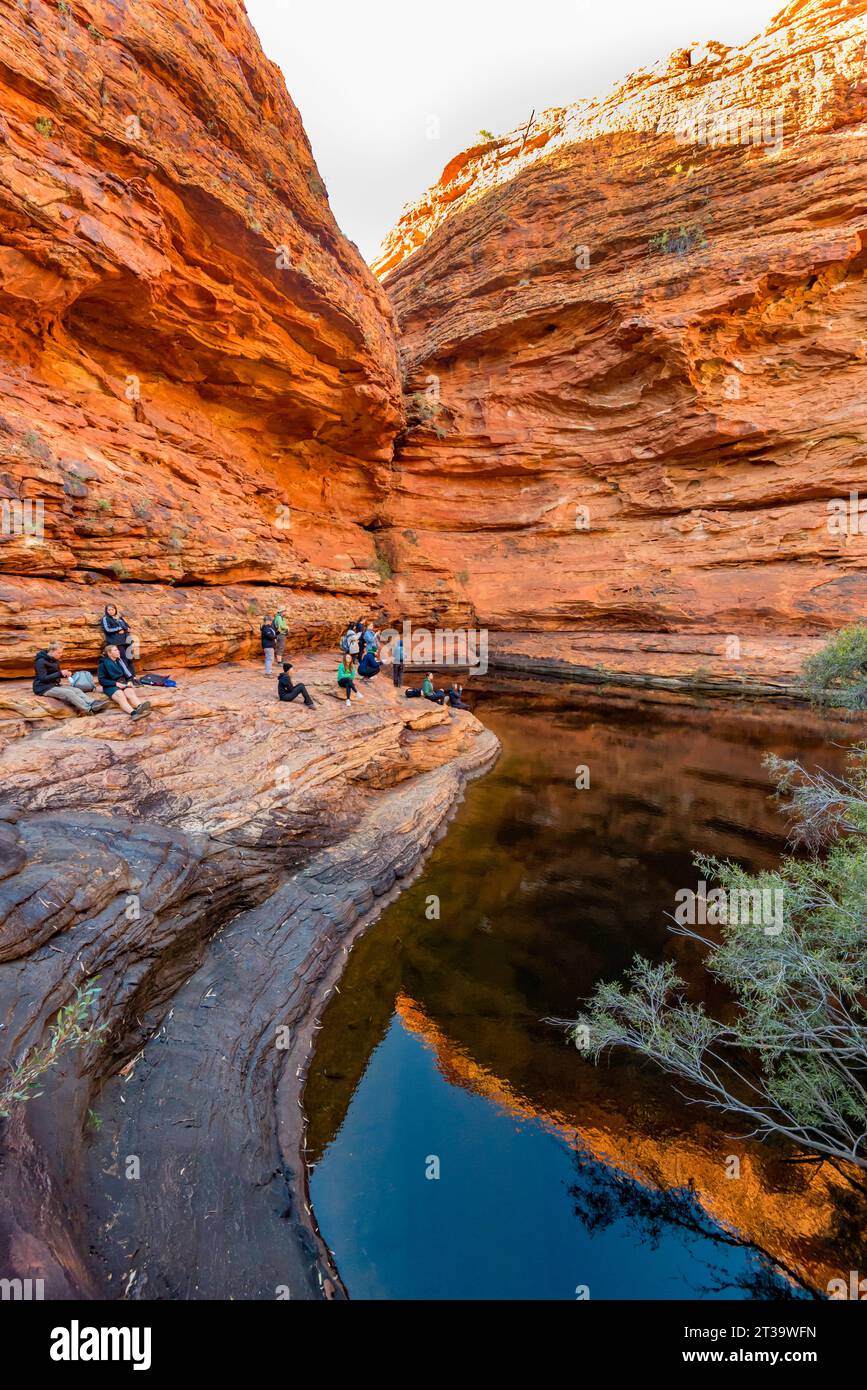Die Menschen versammelten sich kontemplativ im Garden of Eden, einem ständigen Wasserloch am Kings Canyon (Watarrka) im Northern Territory von Australien Stockfoto