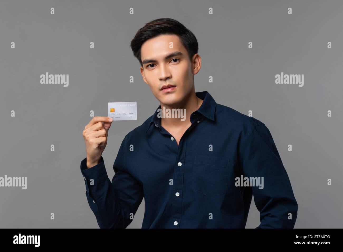 Hübscher asiatischer Mann, der Kreditkarte in hellgrauem isoliertem Hintergrund-Studio-Aufnahme zeigt Stockfoto