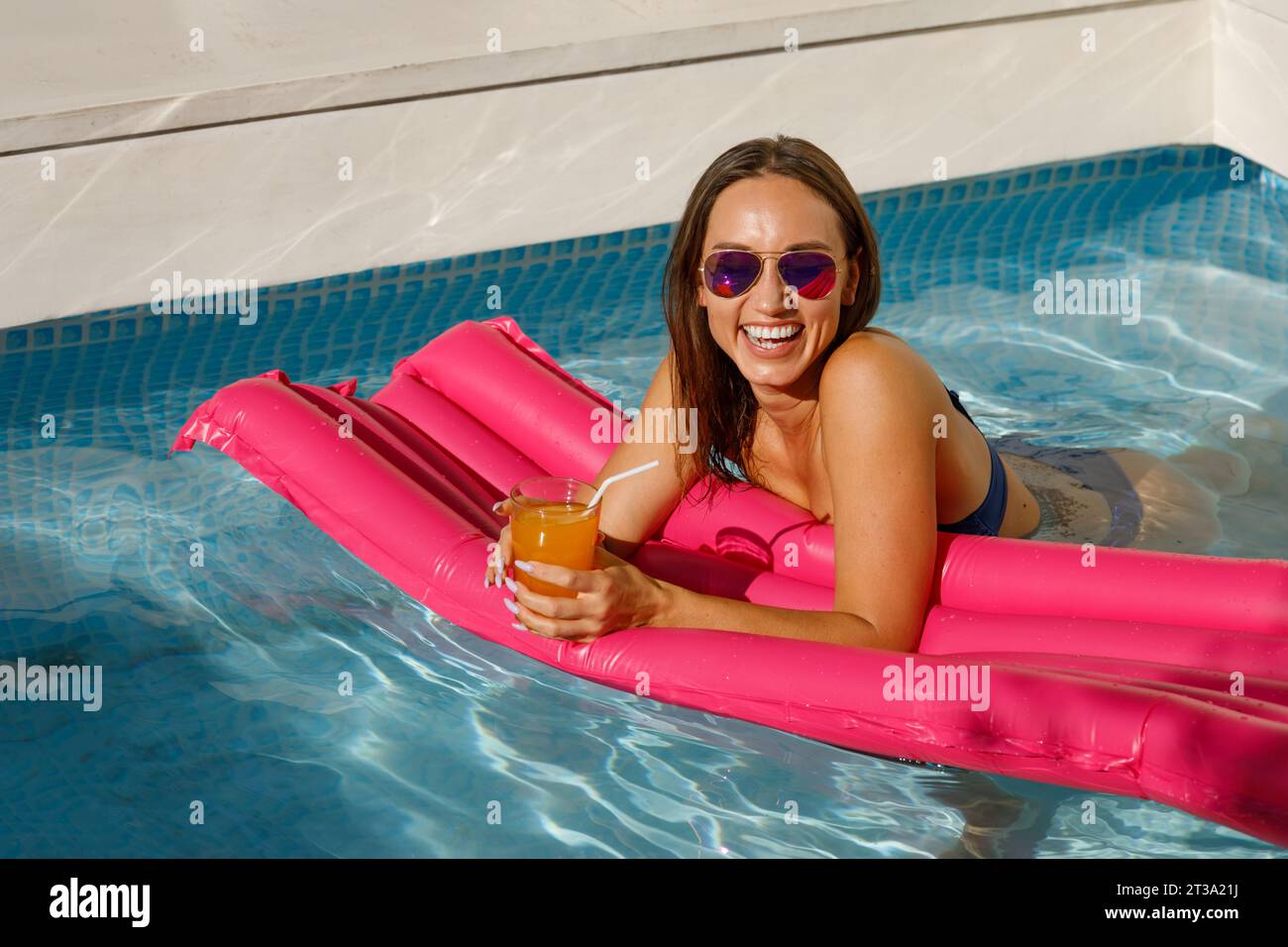 Eleganz am Pool: Wunderschöne Frau, die auf aufblasbarer Matratze liegt Stockfoto