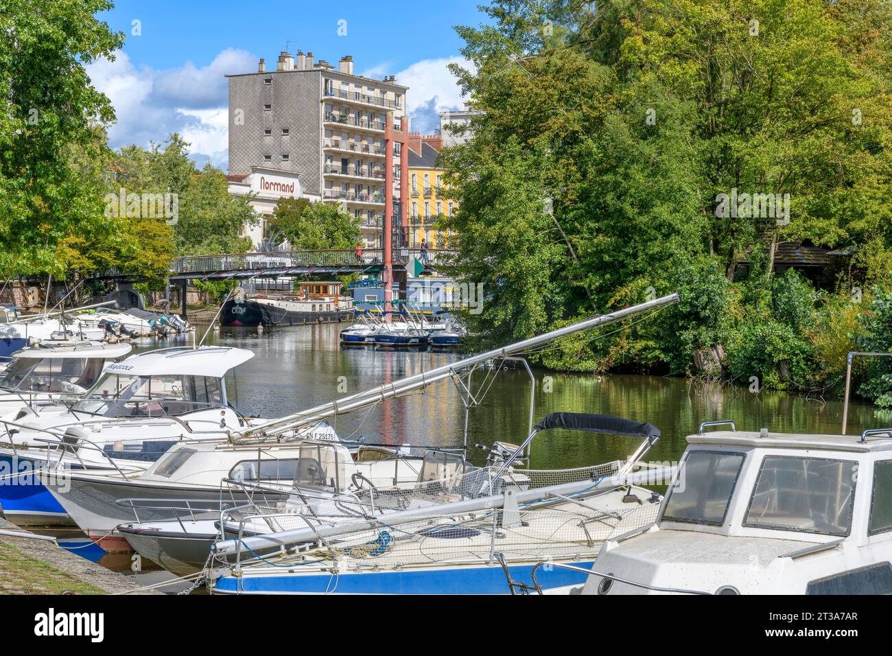 Blick vom Flussufer auf dem Quai de Versailles auf Yachten, Boote und Hausboote auf dem Erdre. Die Fußgängerbrücke verbindet die Insel L'Ile de Versailles. Stockfoto