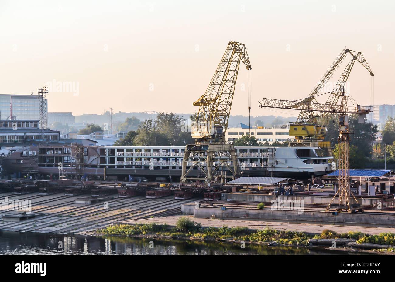 Baukrane und Kräne auf dem Hintergrund eines Flusses in einem Hafen der Stadt. Der Kran ist das Geschäftsgebäude im Hafen von Mo Stockfoto