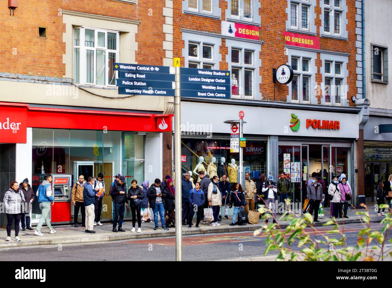 Leute warten an der Bushaltestelle hinter dem Richtungsschild High Road, Wembley, Borough of Brent, London, England, Großbritannien Stockfoto