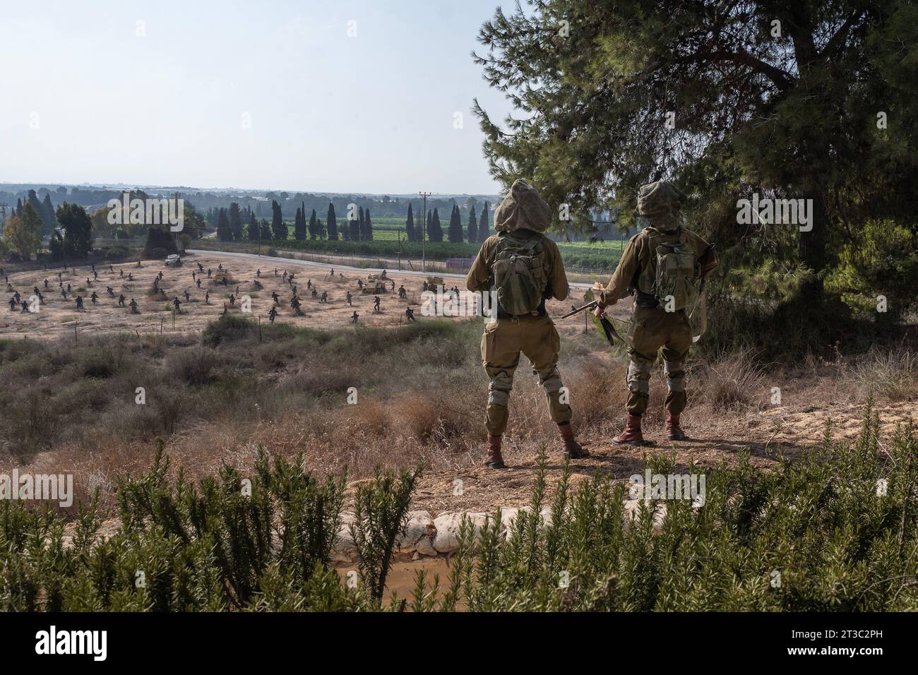 Israelische Infanterie-Soldaten stehen am 24. Oktober 2023 auf den Feldern am Stadtrand von Yad Mordechai entlang der Grenze zum Gazastreifen Wache. Dahinter befinden sich ausgeschnittene Kämpfer, die zeigen, wo die Schlacht im Unabhängigkeitskrieg 1948 stattfand und ägyptische Soldaten abgestoßen wurden. Zu der Gemeinde gehört auch das Holocaust-Revival-Museum, das gestern, den 23. Oktober 2023, von einer Hamas-Rakete, die aus dem Gazastreifen abgefeuert wurde, direkt auf das Dach getroffen wurde. Das Museum zeigt das Leben im Warschauer Ghetto und wie die Jüdische Kampforganisation unter dem Kommando von Mordechai Anielewicz in den letzten Tagen der Fighti lebte Stockfoto