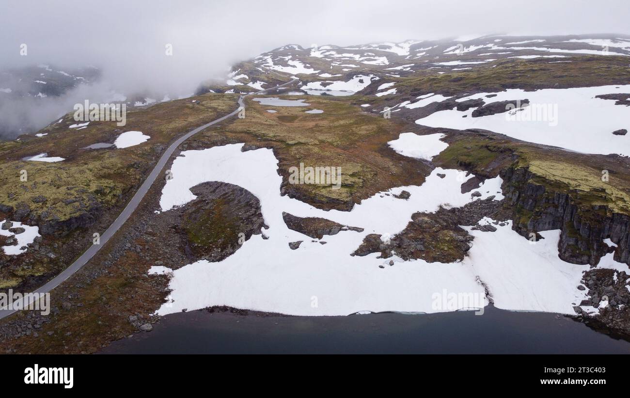 Luftbild der alten Straße über Aurlandsfjell mit Schneefeldern im Frühsommer Stockfoto