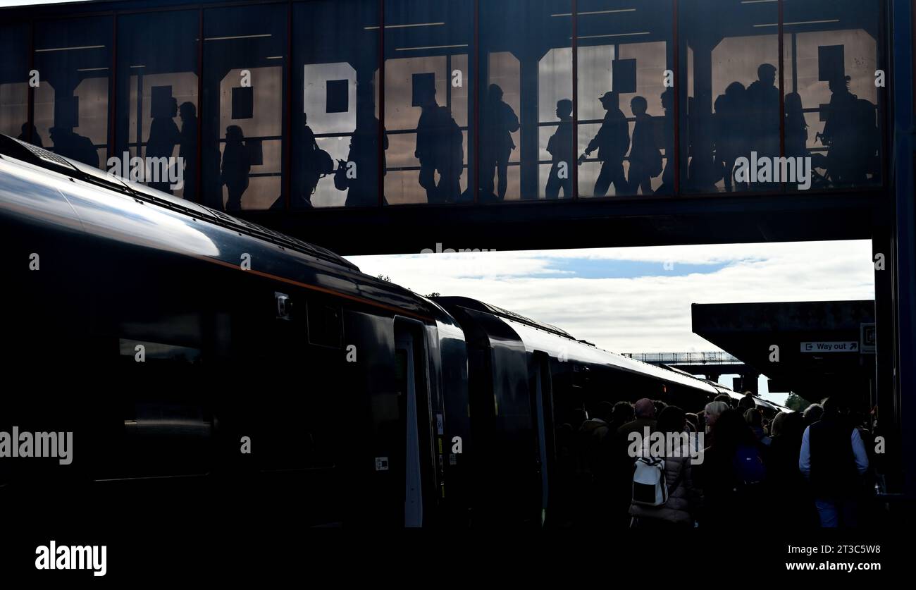 Silhouetten von Menschen beim Überqueren der Eisenbahnbrücke am Bahnhof, Großbritannien Stockfoto